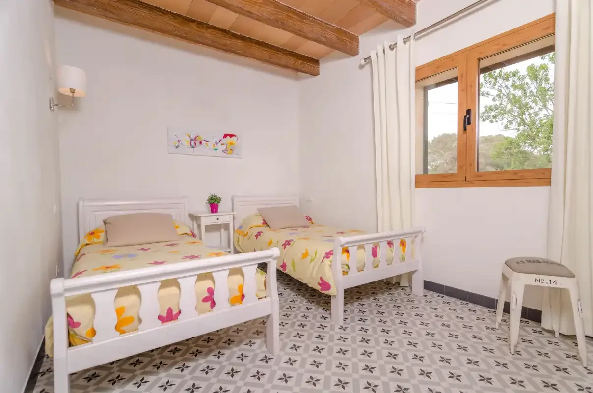 Un dormitorio luminoso con dos camas y una ventana con marco de madera.