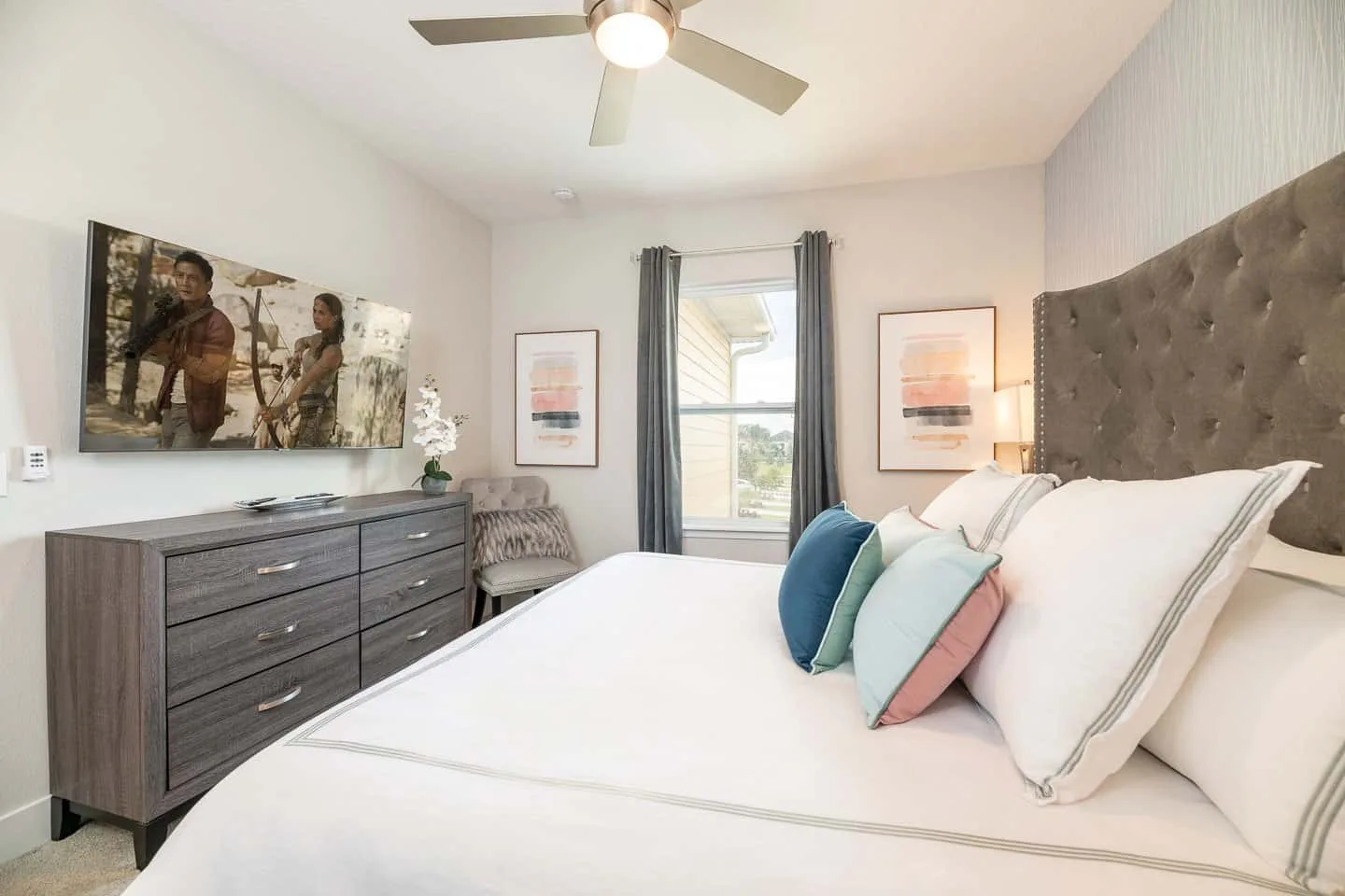 A bright bedroom with a neatly made bed and a dresser along the wall.