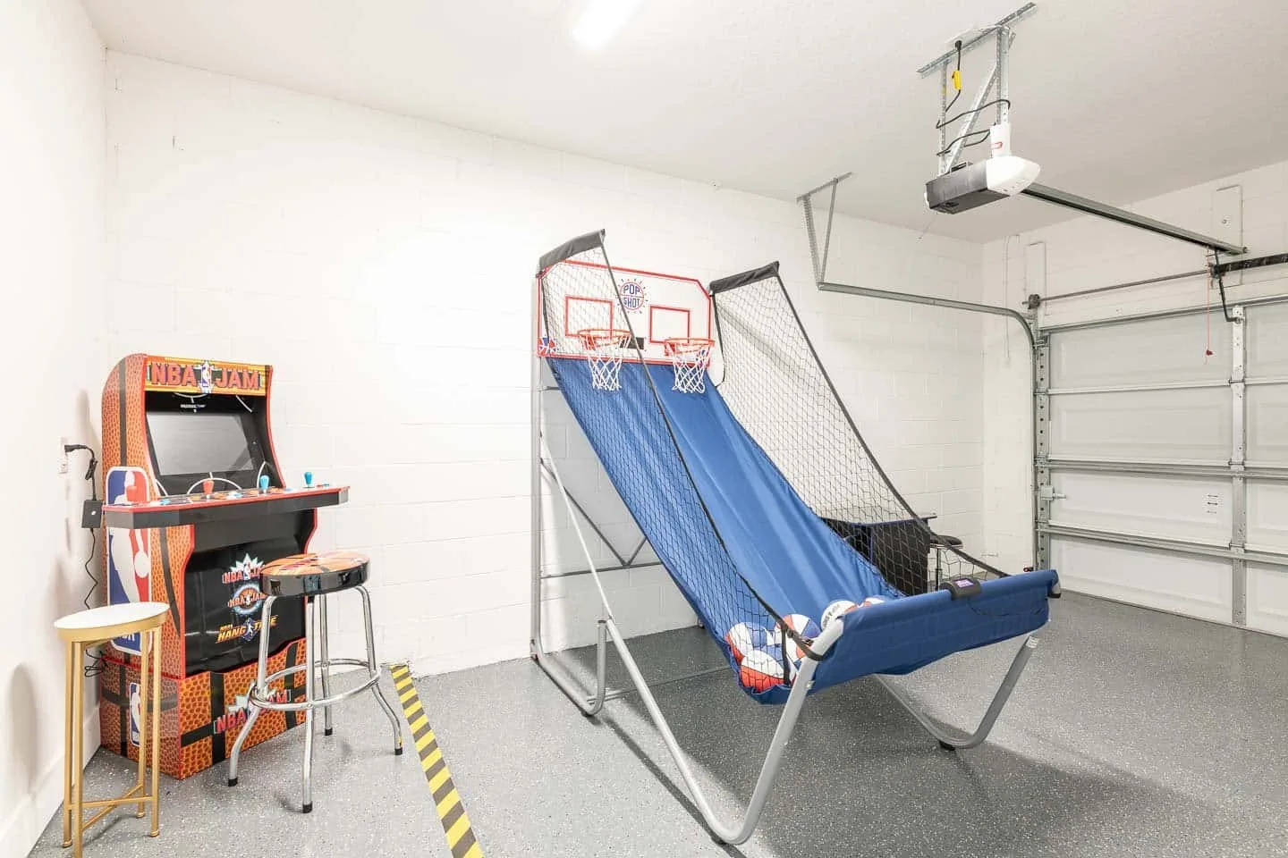 A garage game area with an arcade machine and basketball game.