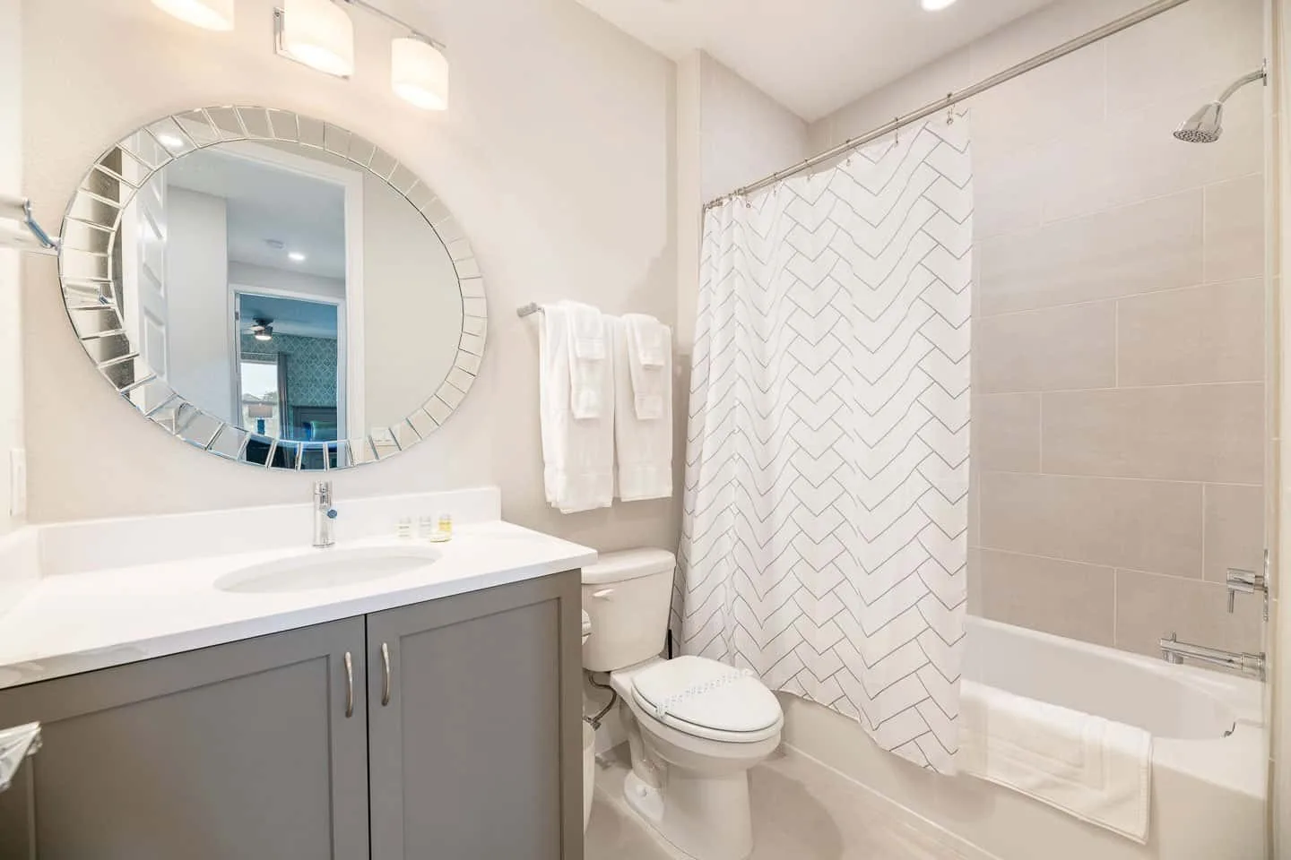 A bathroom with a sink, toilet, and bathtub behind a patterned shower curtain.