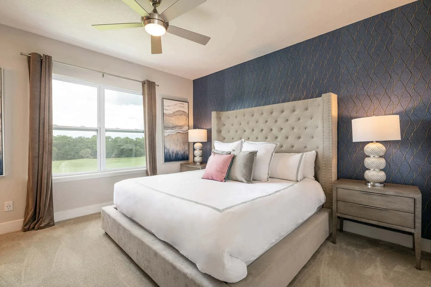 A bedroom with a neatly made bed, bedside tables, and a large window.