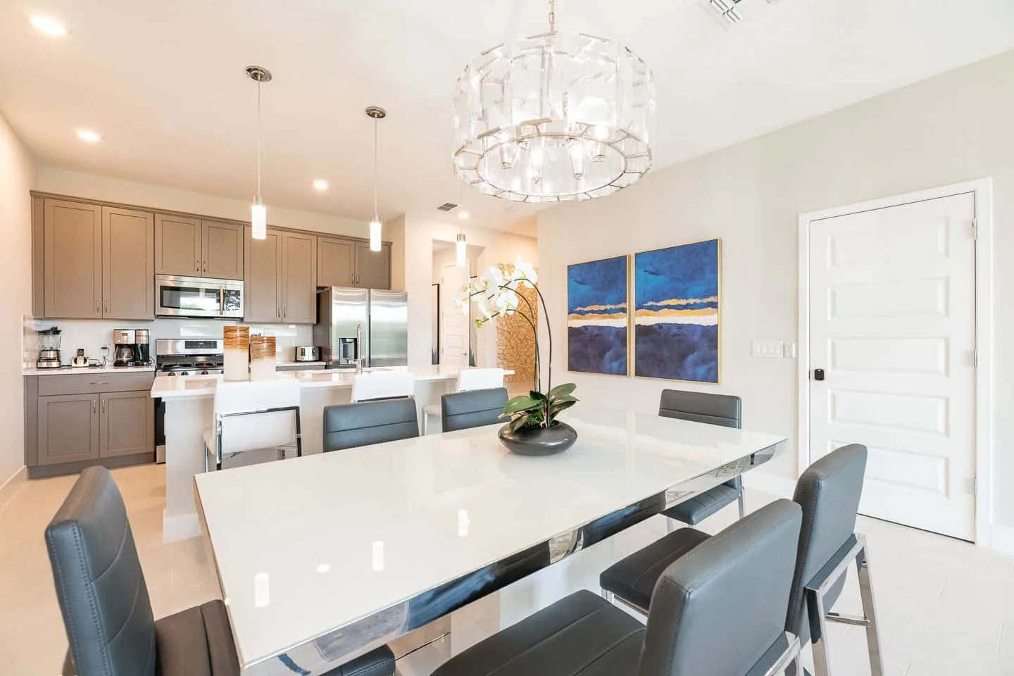 A dining area with a long table and seating, opening onto a kitchen.