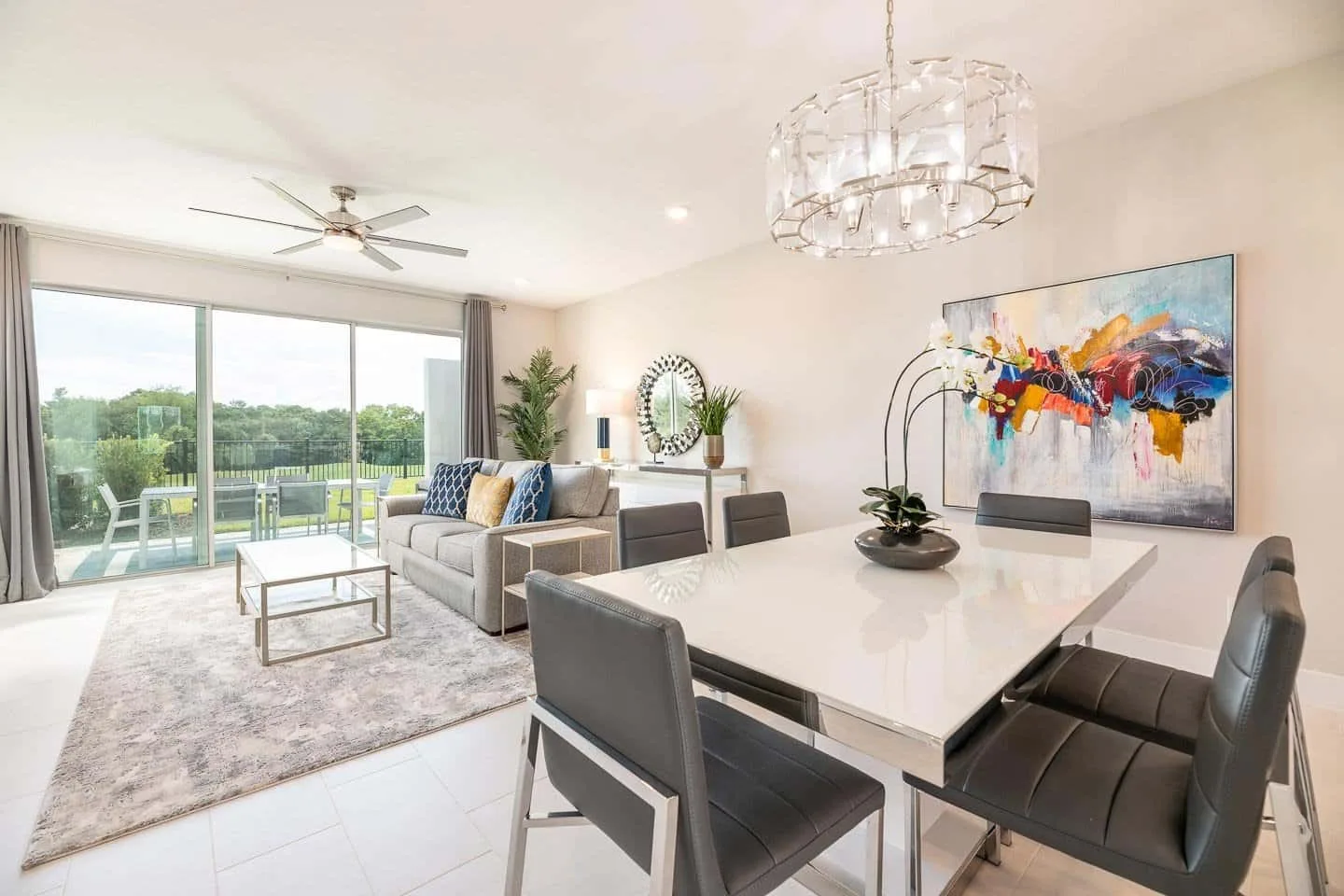 A bright living and dining area opens onto a balcony, with a large table and seating.