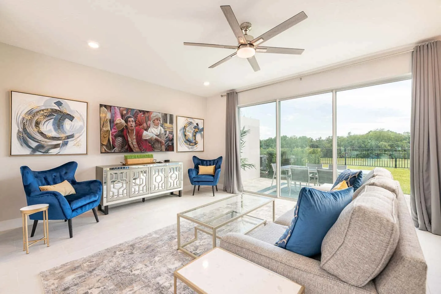 A bright living room with seating, wall art, and sliding glass doors opening to a balcony.