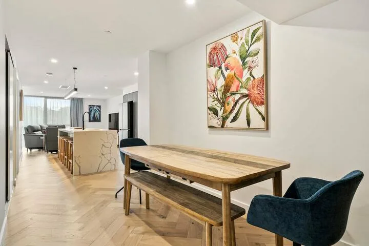 A dining area with a wooden table, bench, and colorful botanical artwork.