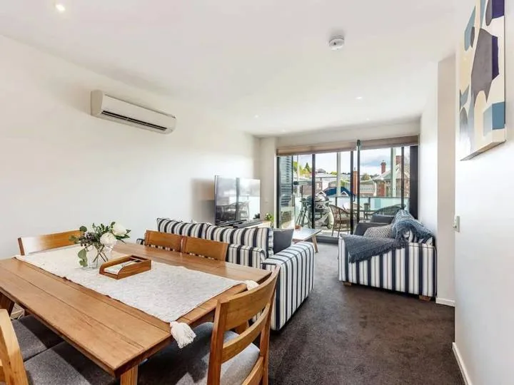 A bright living and dining area with striped seating and sliding glass doors.