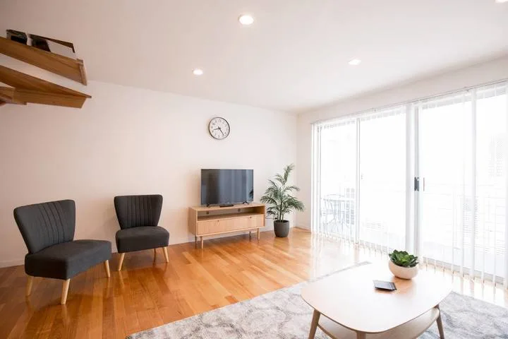 A bright living room with seating, a television, and large windows.