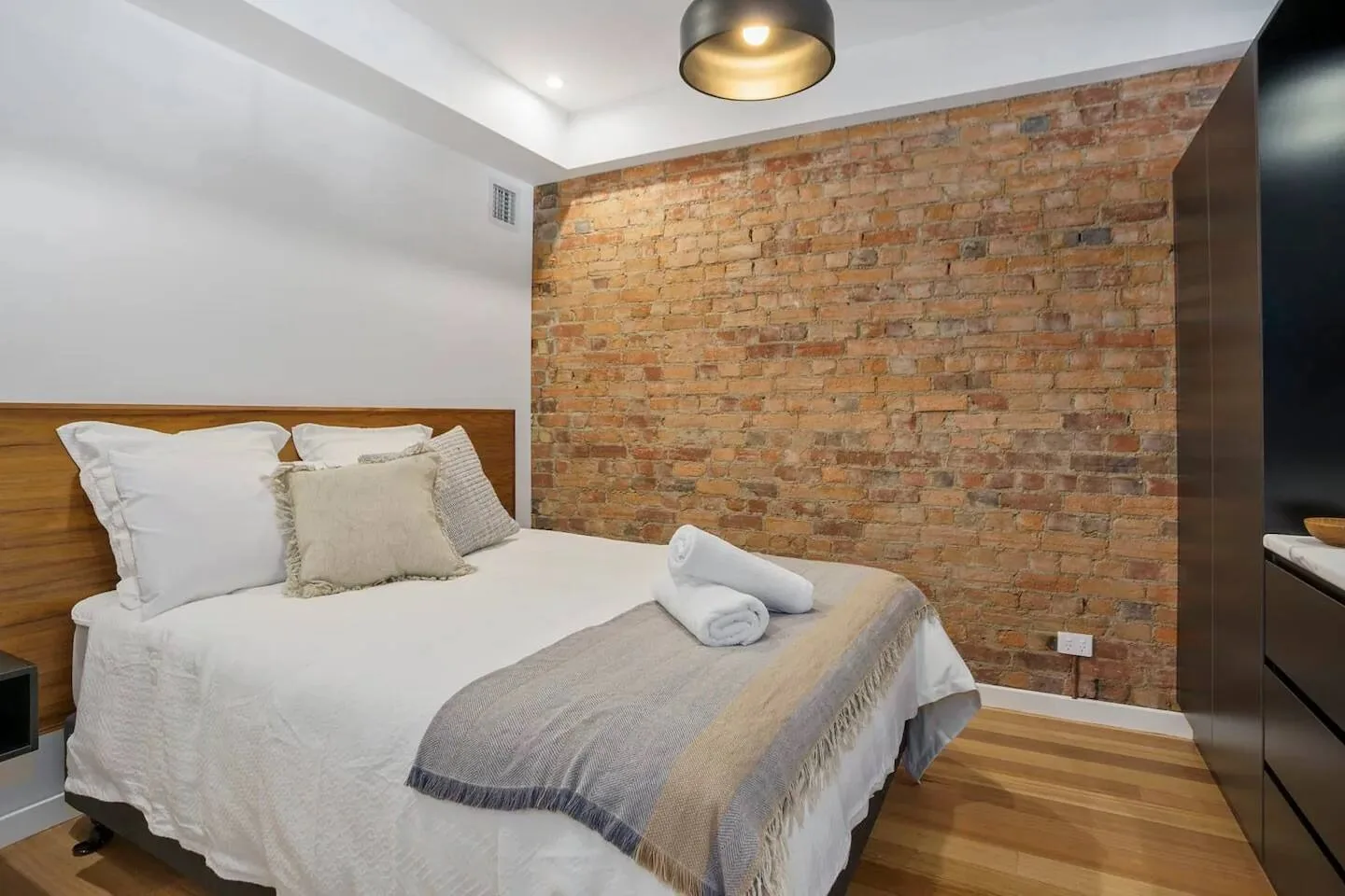 A bedroom with a bed and exposed brick wall.