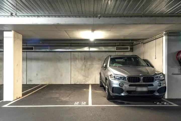 An indoor parking garage with a car parked beside marked spaces.