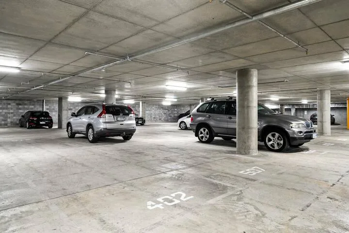 An indoor parking garage with parked cars beneath a low concrete ceiling.