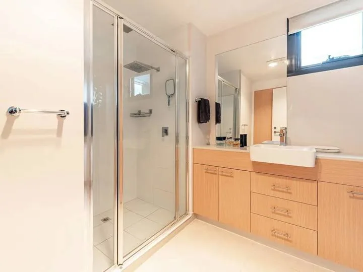 A bright bathroom with a glass shower and a sink vanity.