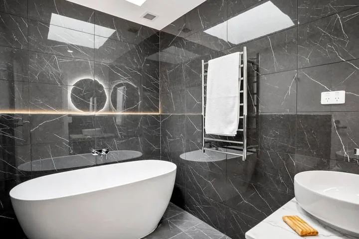 A modern bathroom with a freestanding bathtub, wall-mounted towel warmer, and vessel sink.
