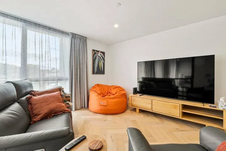 Living room with seating, a large television, and a bright orange beanbag.