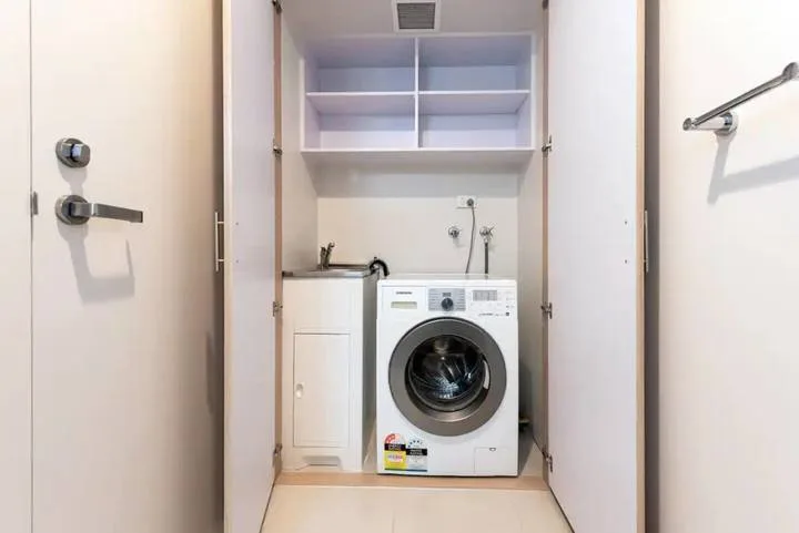A laundry area with a front-loading washing machine beneath open shelves.