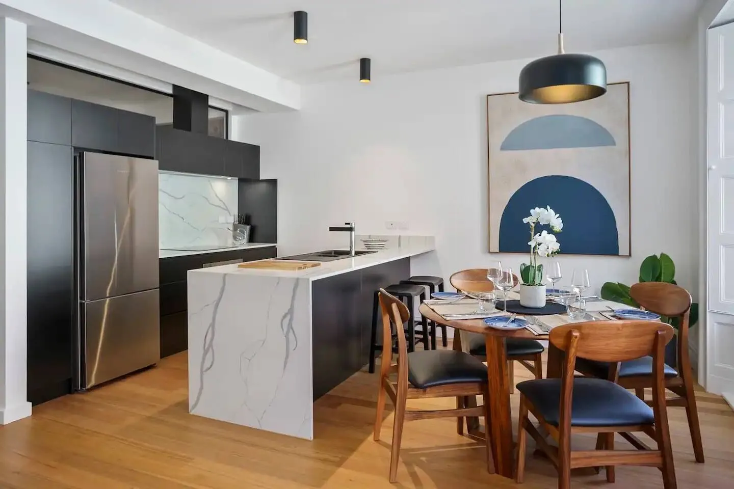Un comedor con una mesa de madera y sillas está junto a una cocina abierta.