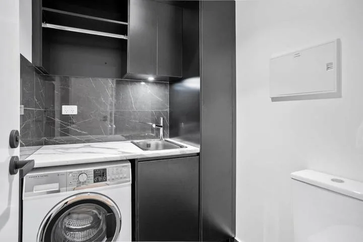 A compact laundry area with a washing machine beneath a countertop and sink.