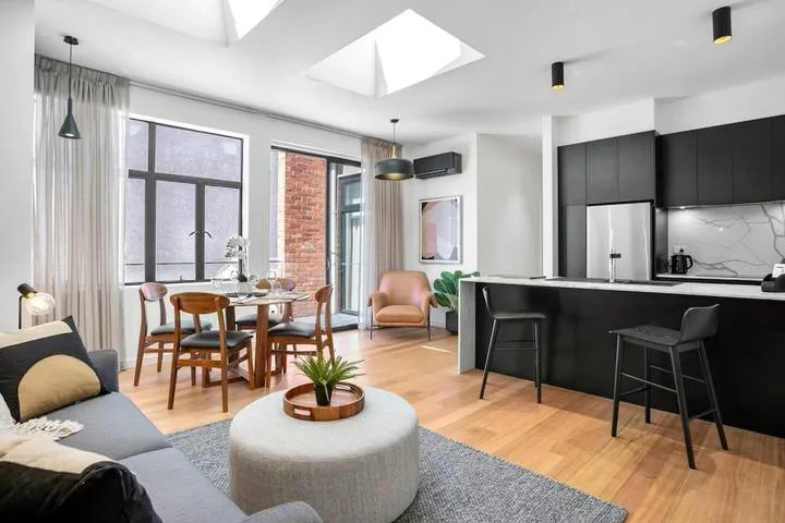 A bright open-plan living and dining area with a kitchen counter and large windows.