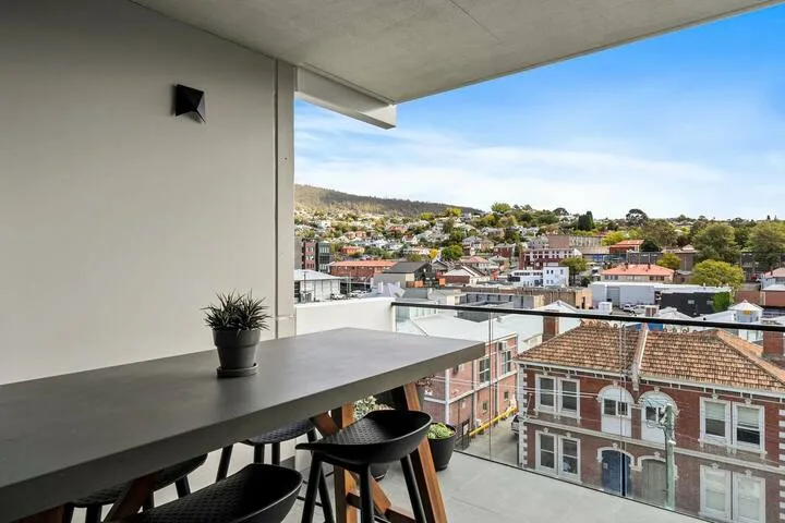 A balcony seating area overlooks a neighborhood of buildings and trees.