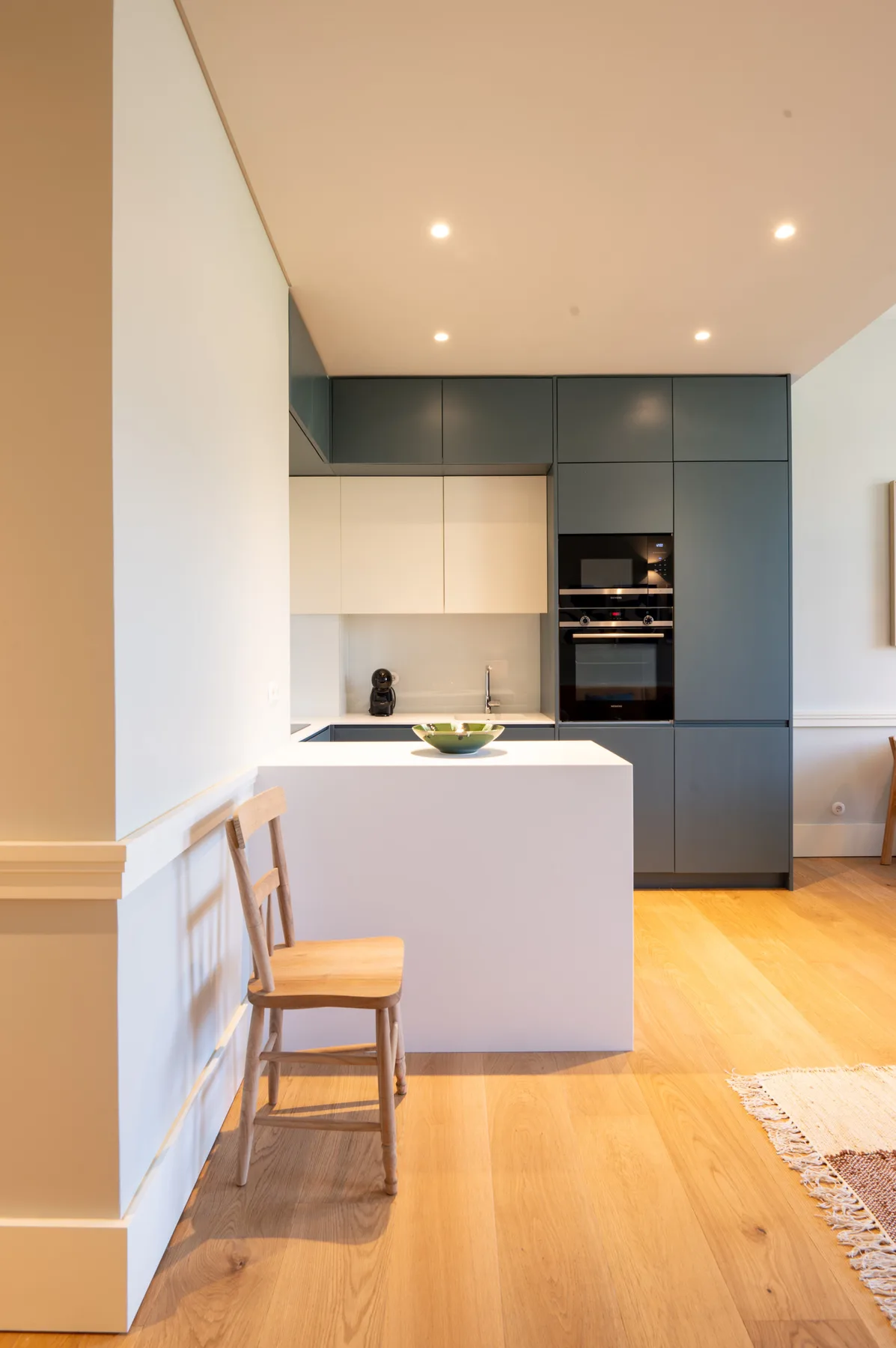 Una cocina moderna con una isla blanca y suelo de madera.