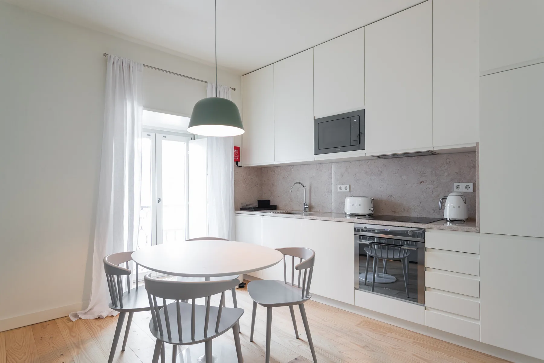 Una cocina luminosa con zona de comedor y una mesa redonda junto a la ventana.
