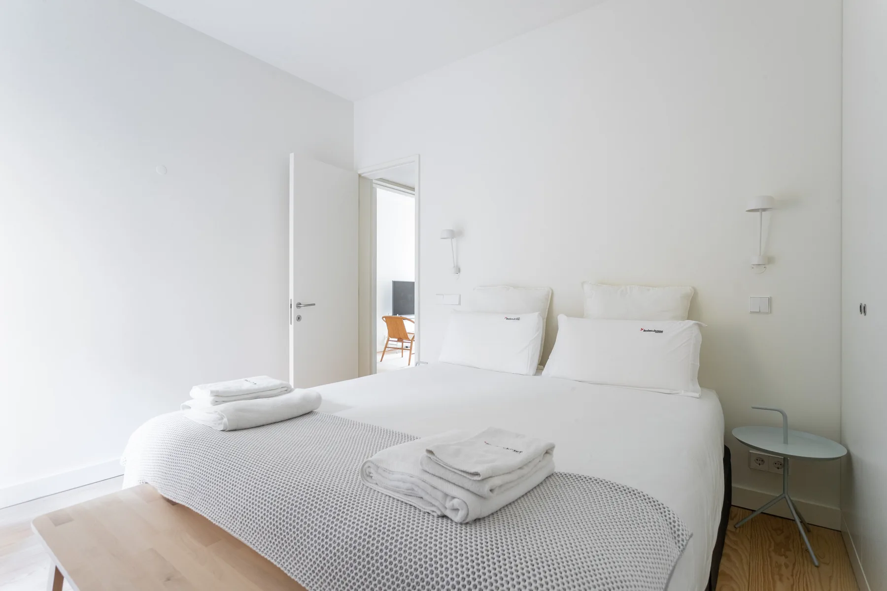 Un dormitorio luminoso con una cama bien hecha y toallas dobladas.