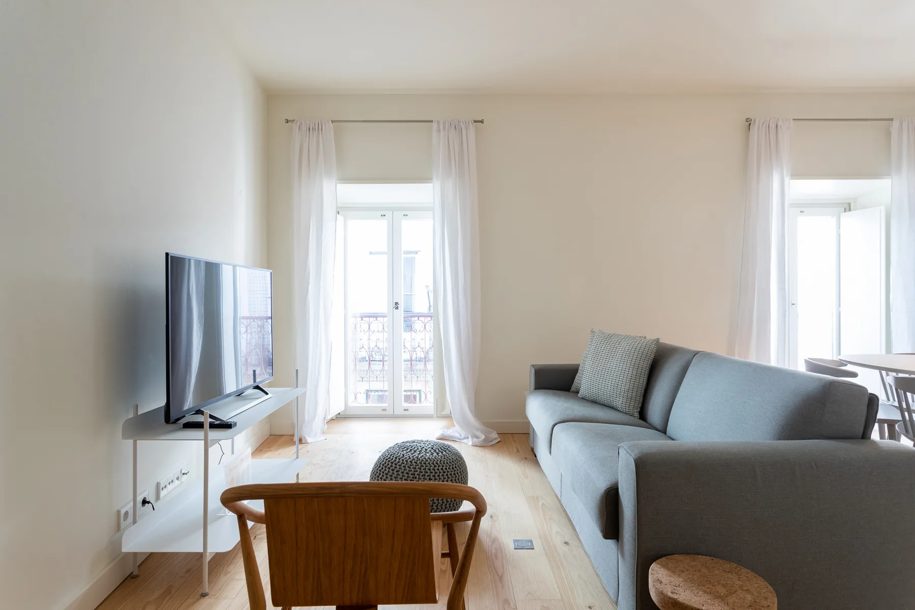 Una sala luminosa con asientos, un televisor y ventanas altas.