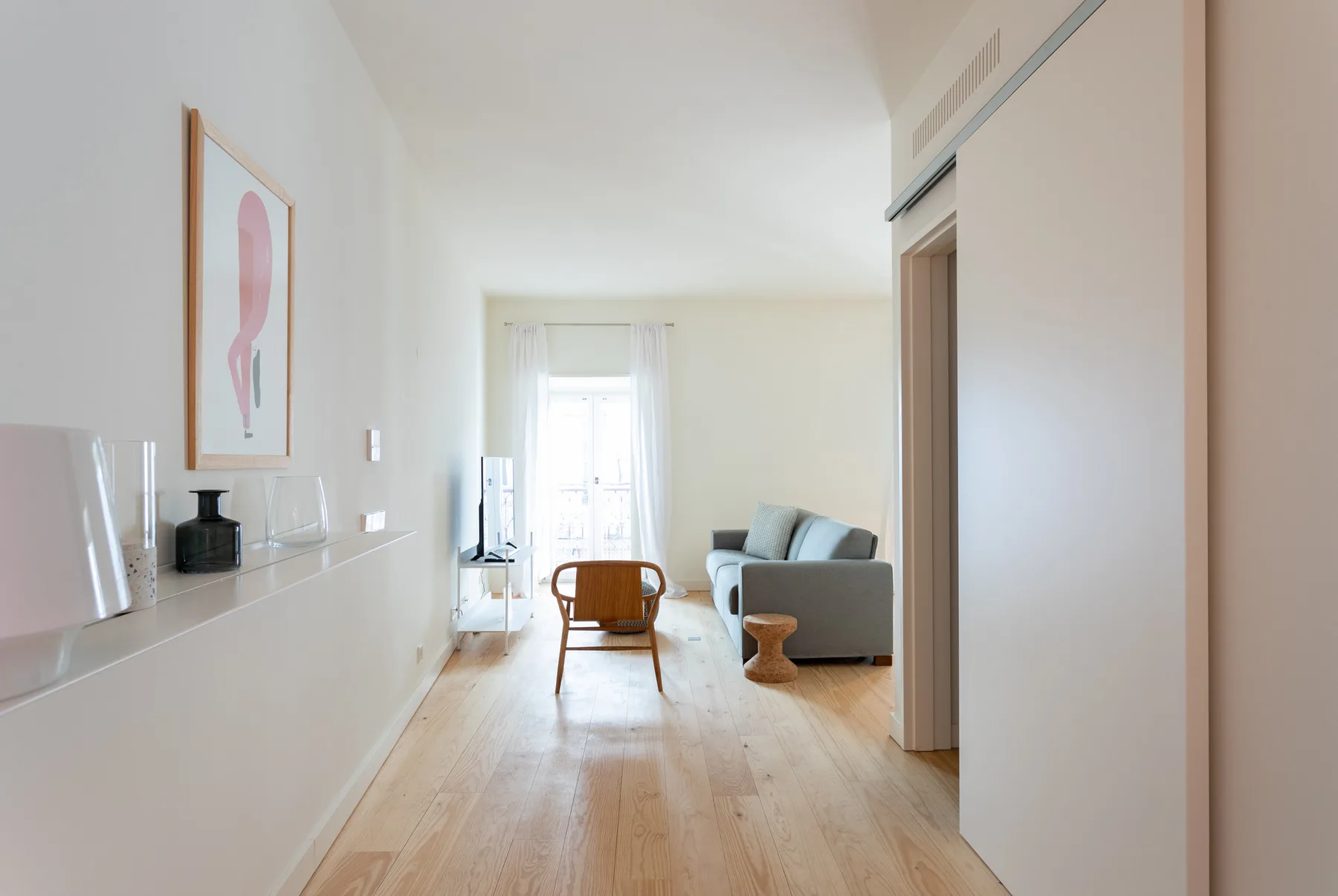 Una sala de estar luminosa con asientos y una mesa pequeña junto a una ventana.