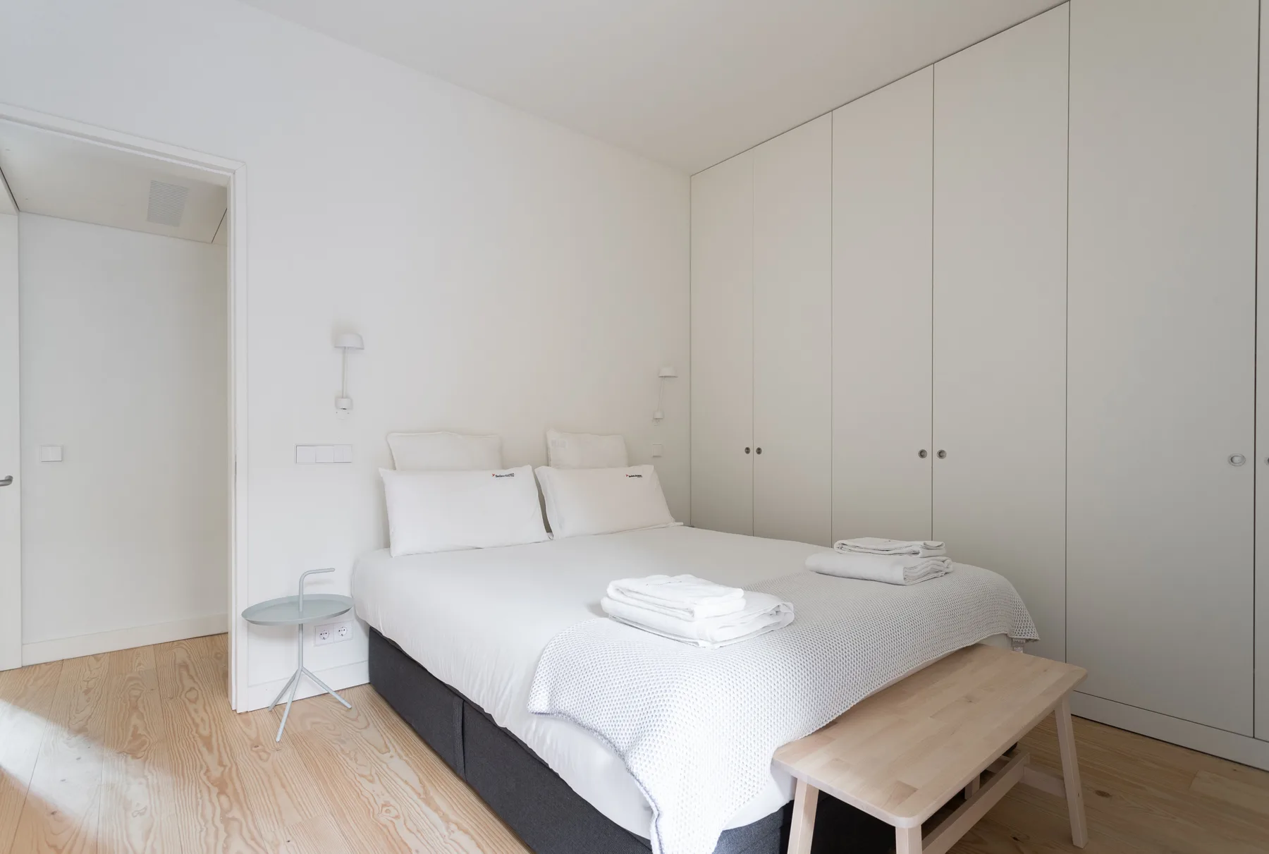 Un dormitorio luminoso con una cama bien tendida y armarios empotrados.