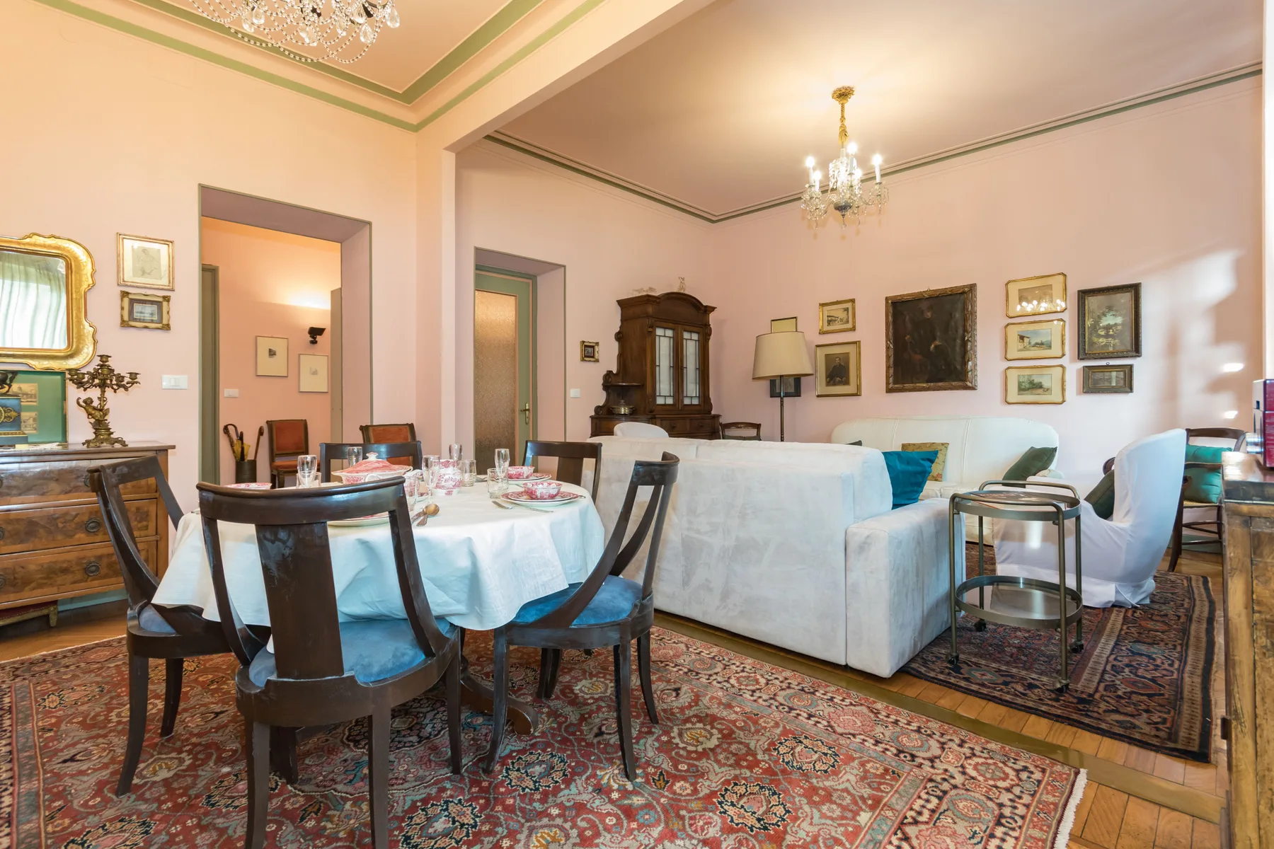 A dining and sitting room with a set table, seating, and framed wall art.