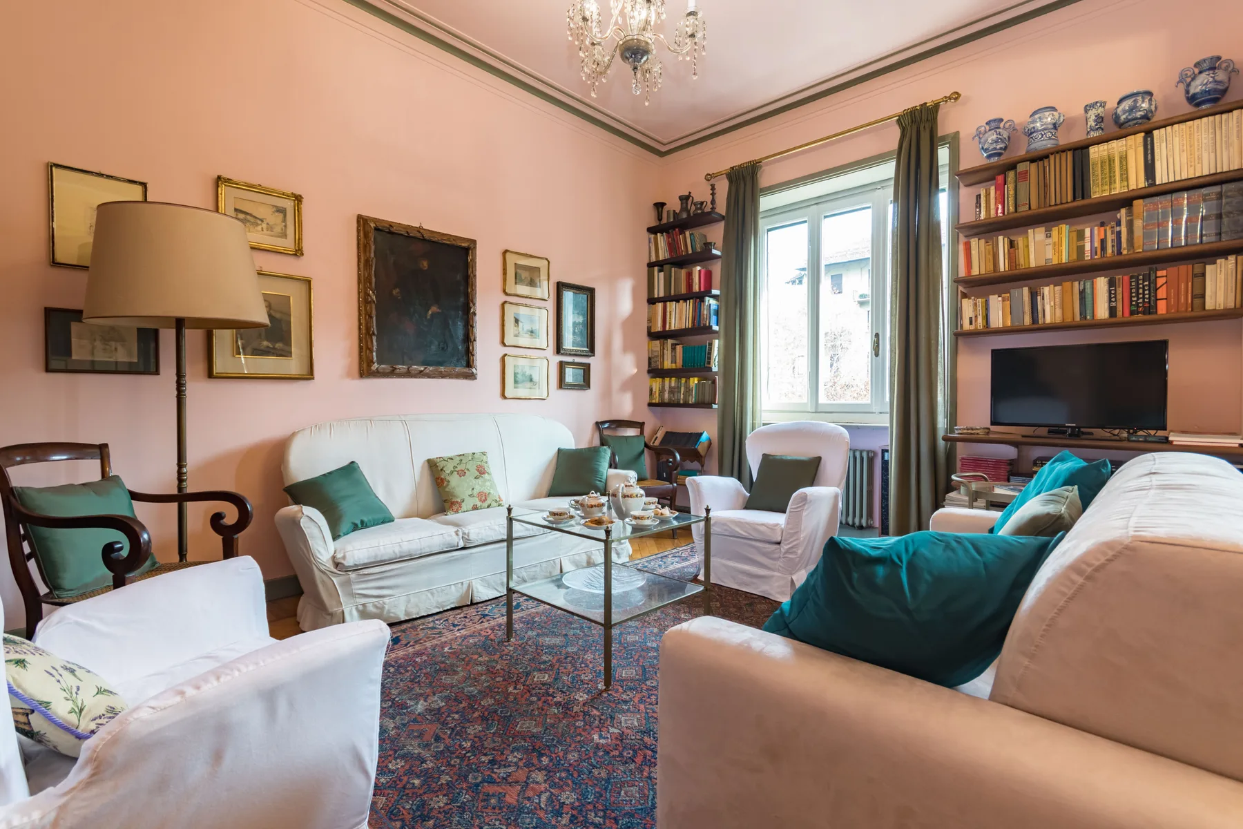 A living room with several seating areas, a glass coffee table, and bookshelves.