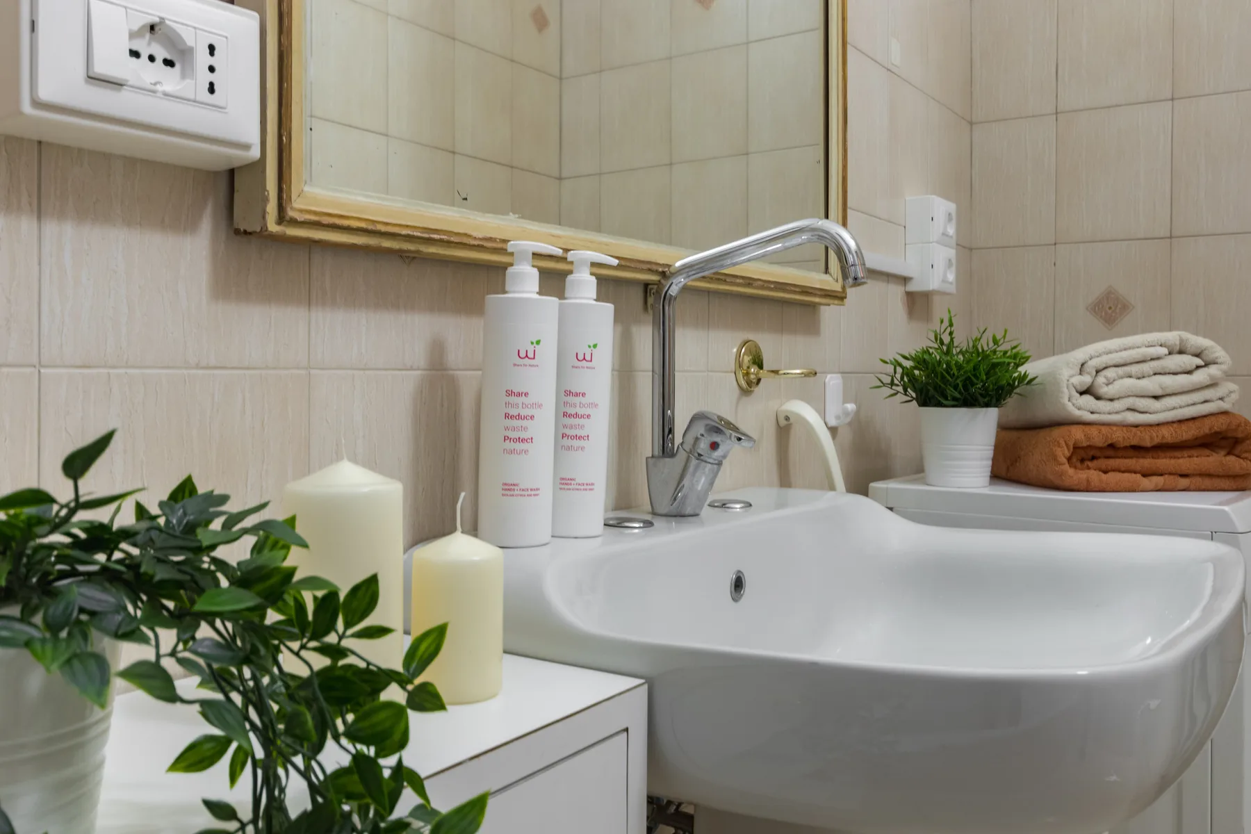 Un lavabo de baño con artículos de aseo y toallas dobladas al lado.
