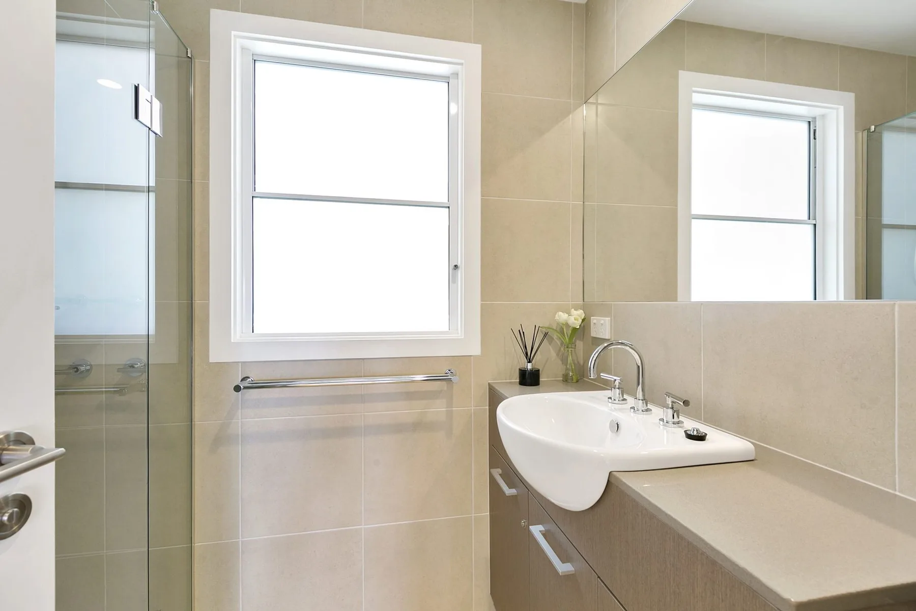 A bathroom with a sink and a window beside the mirror.