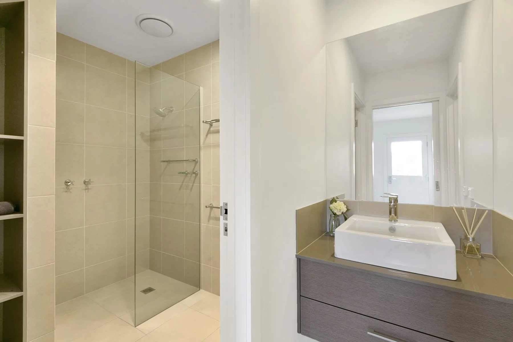 A bright bathroom with a glass shower and a sink vanity beneath a mirror.