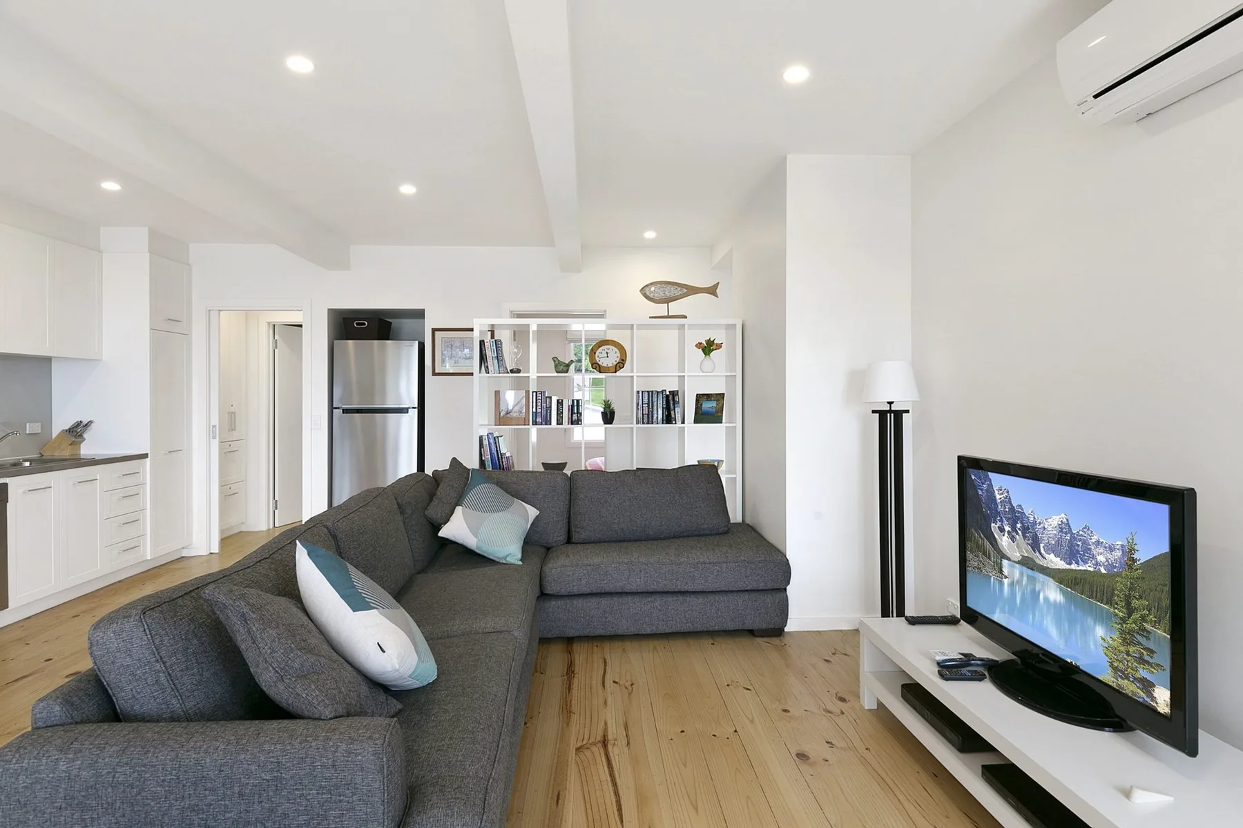 A bright open-plan living room with a gray sectional and television.