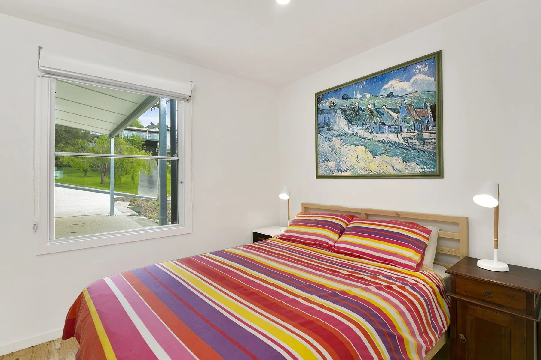 A bedroom with a bed covered in a colorful striped bedspread.