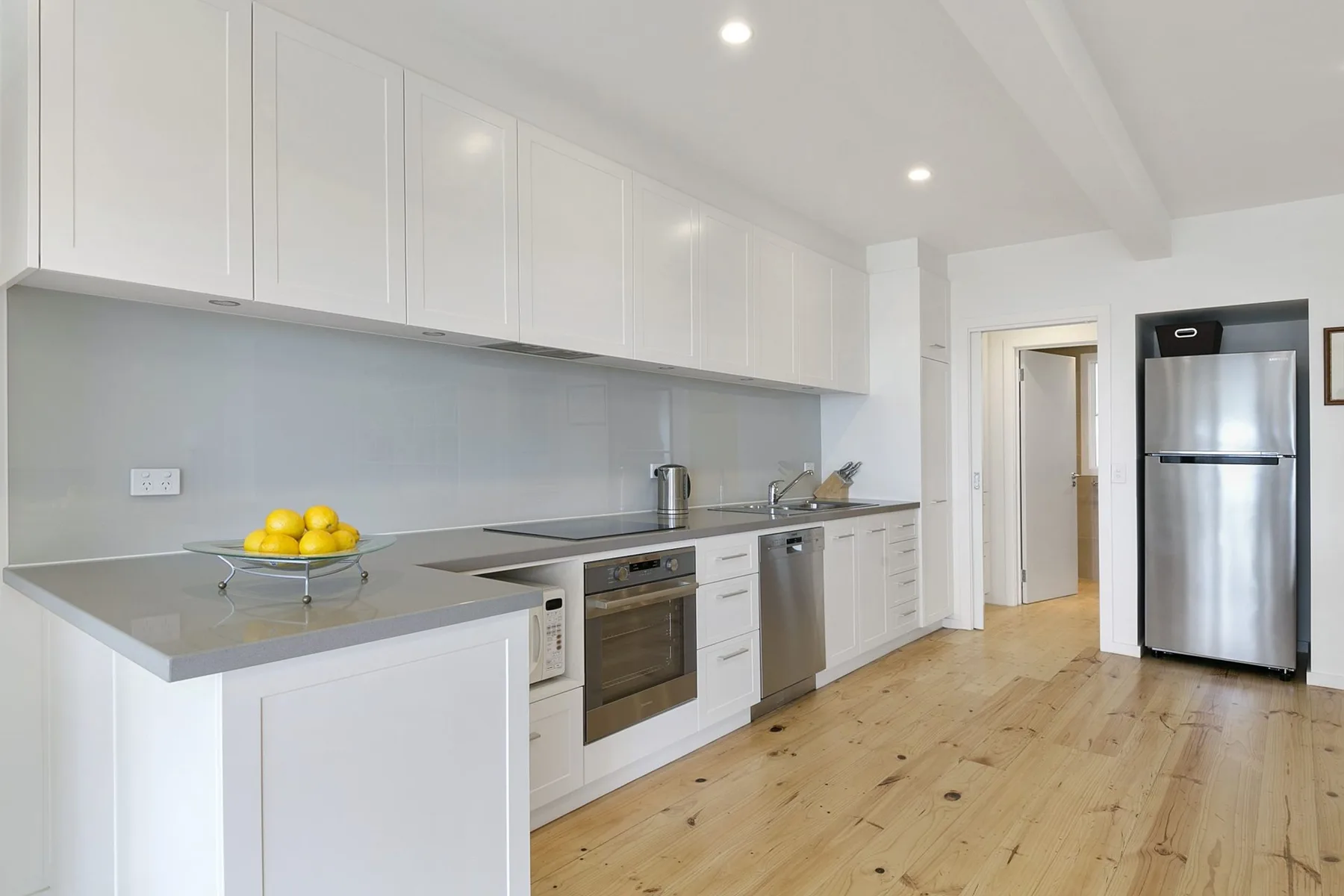 A bright kitchen with white cabinetry, a countertop, and stainless steel appliances.
