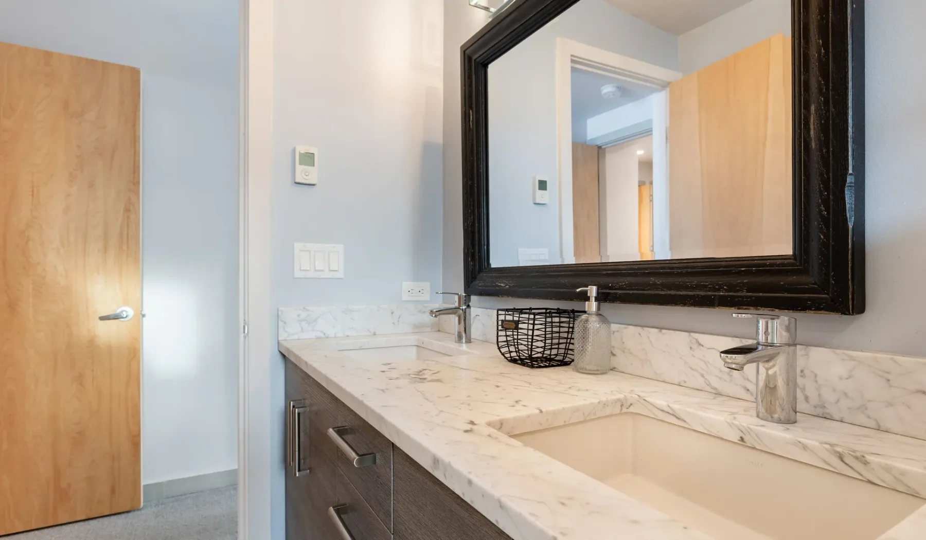 A bathroom vanity with a marble countertop and large framed mirror.
