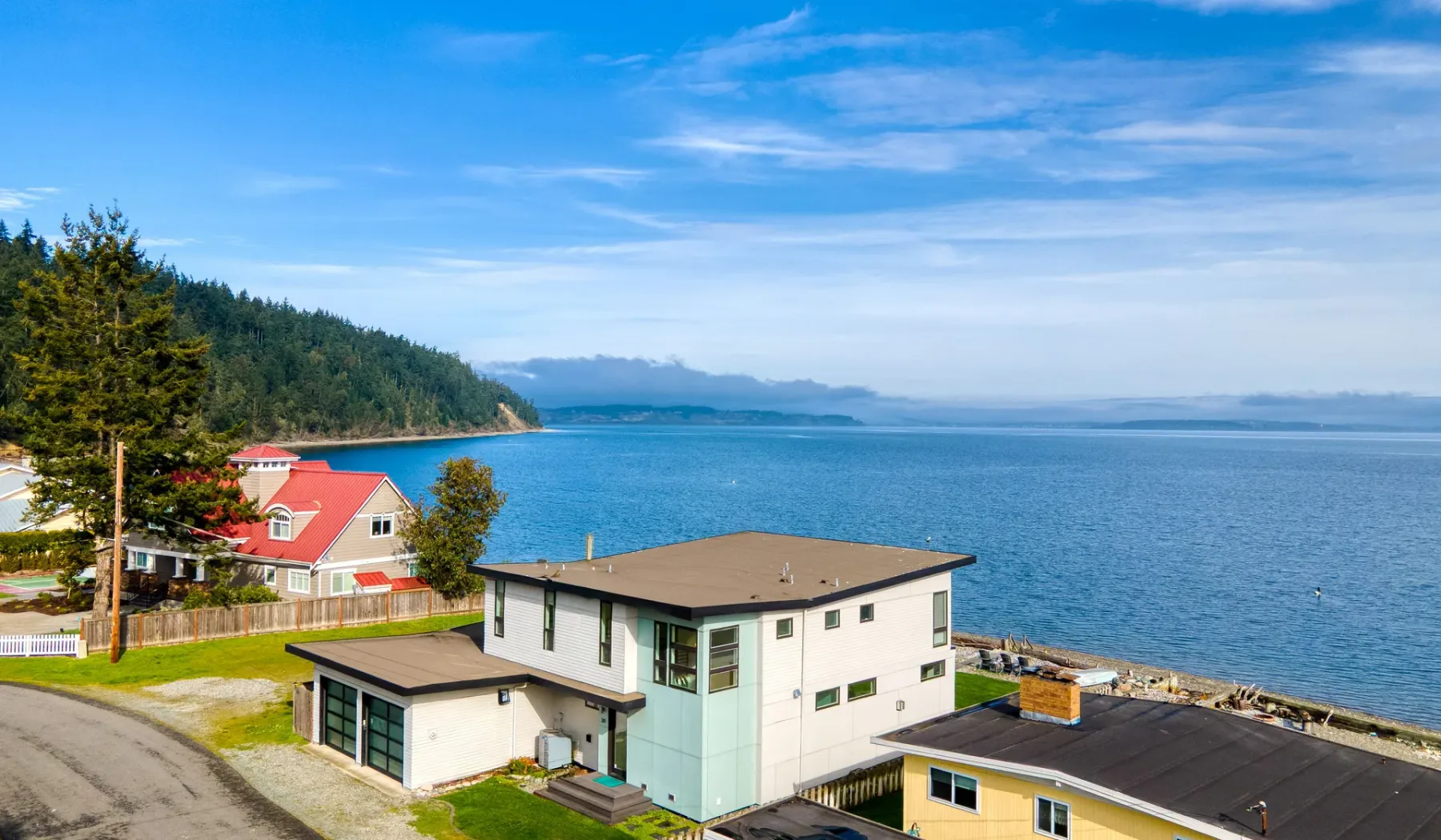 A coastal residential scene with houses beside a broad expanse of water.