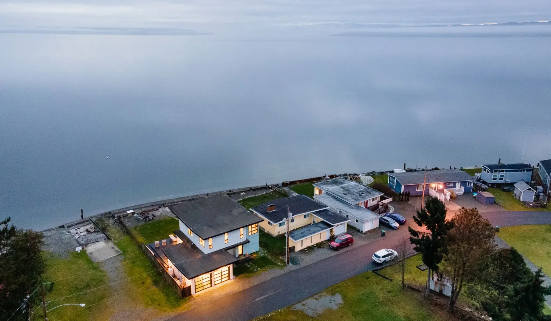 Aerial view of buildings beside a calm body of water at dusk.