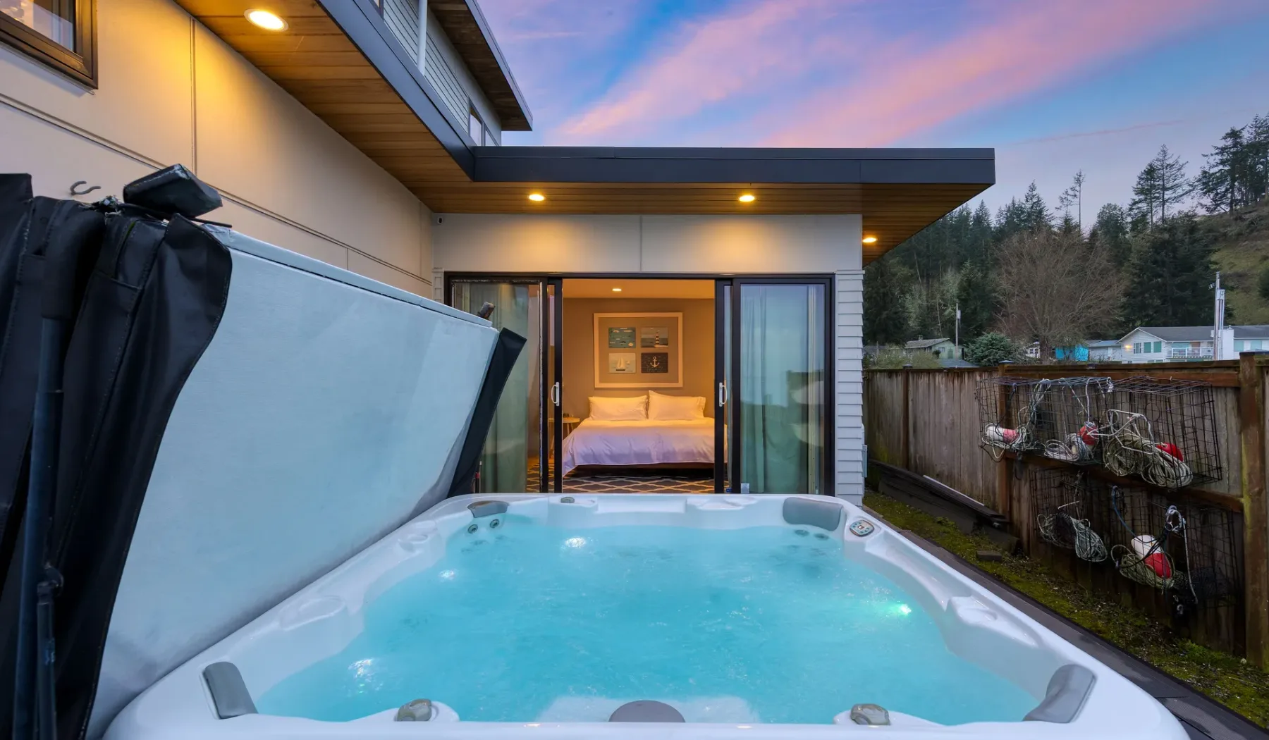 A bubbling outdoor hot tub sits beside a sliding glass door at dusk.