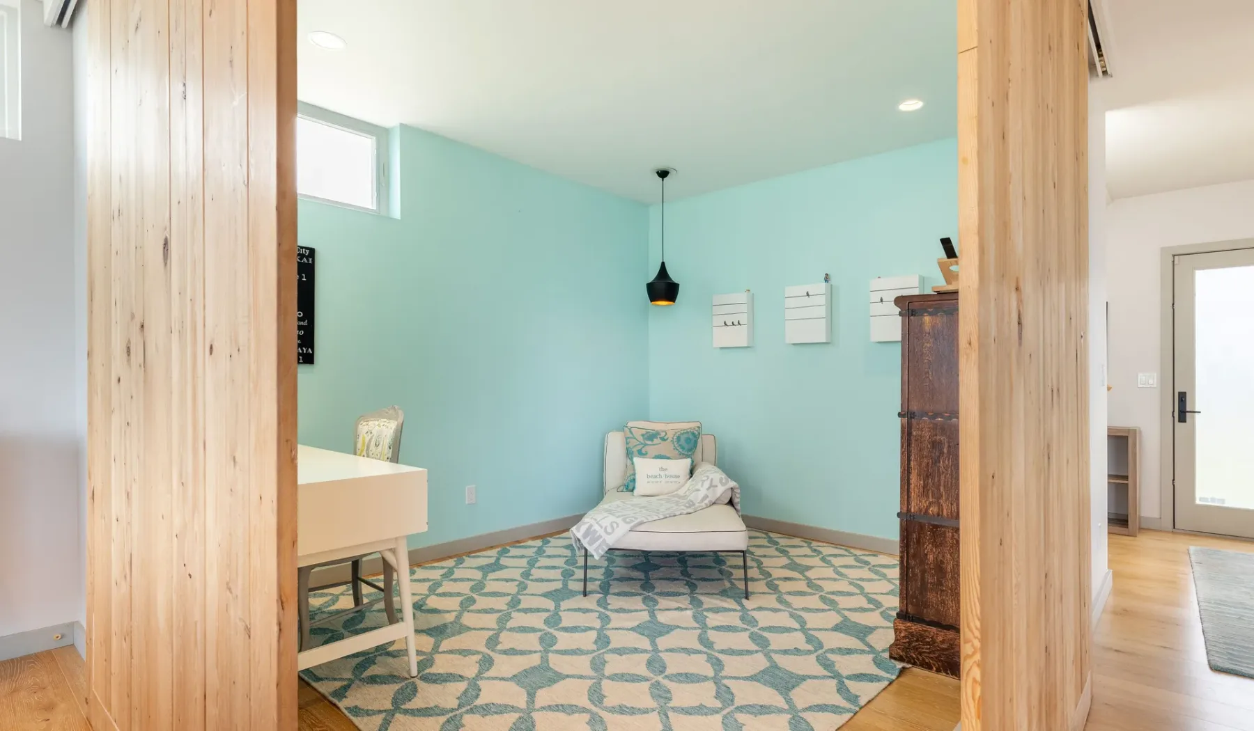 A bedroom with a bed, turquoise walls, and a patterned rug.