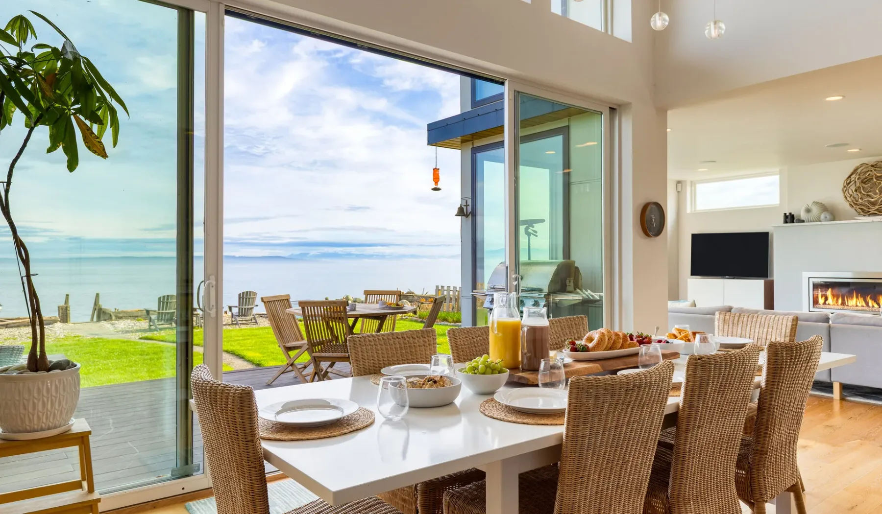 A dining area opens through large glass doors onto a patio overlooking the water.