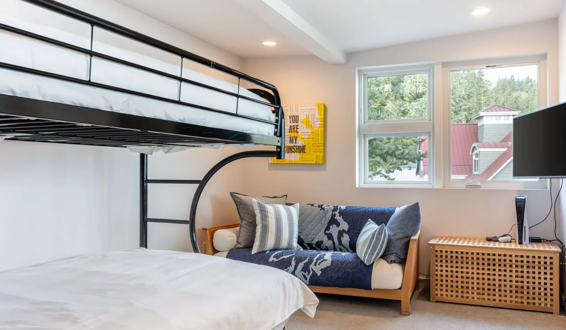 A bedroom with bunk beds, a seating area, and windows overlooking trees.