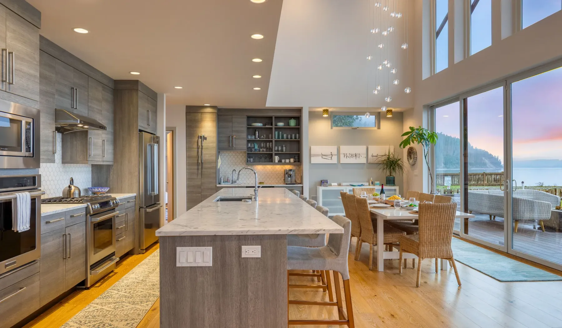 A bright open-plan kitchen and dining area with large windows overlooking the water.