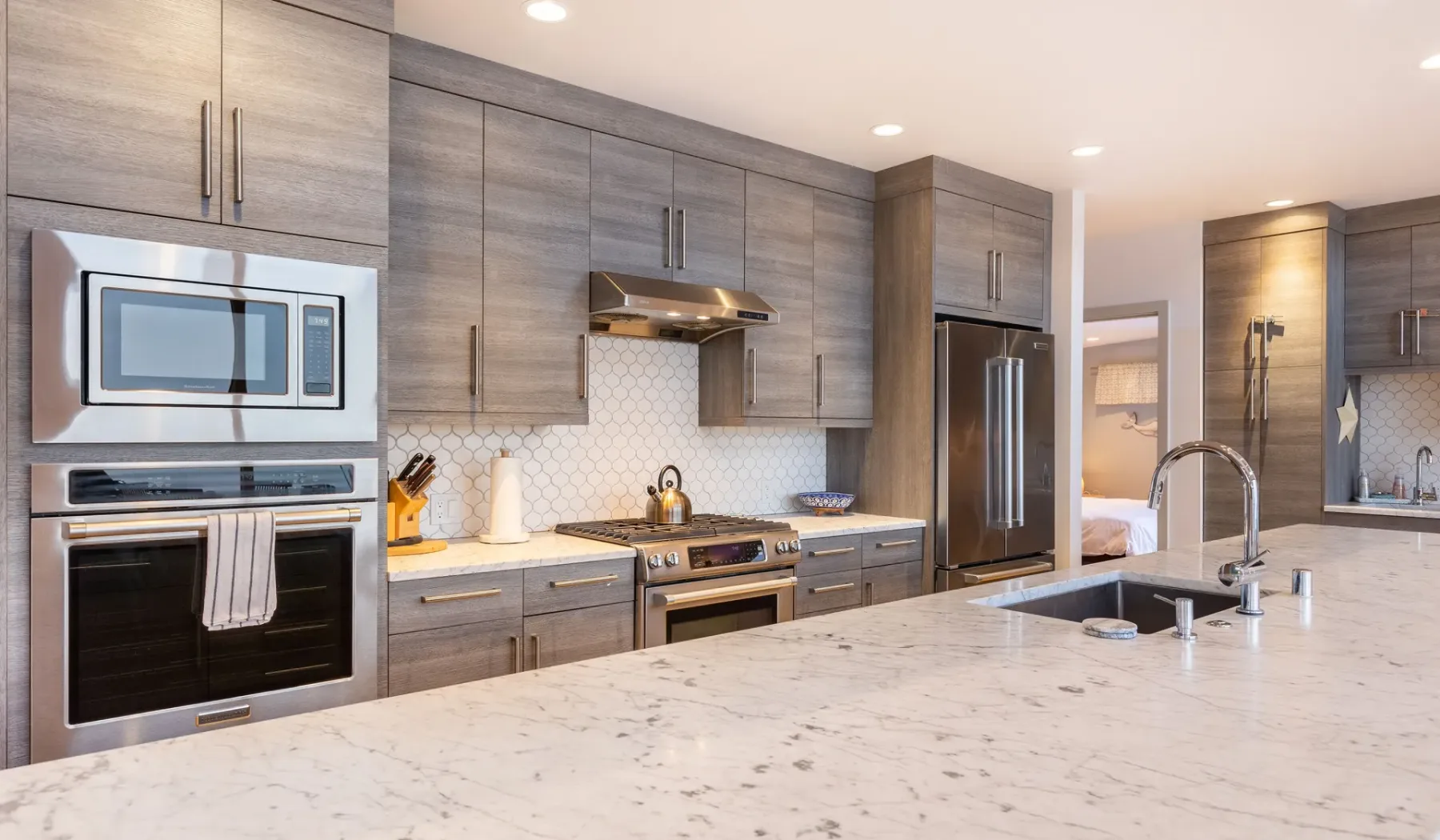A modern kitchen with gray cabinetry, stainless steel appliances, and a large island.