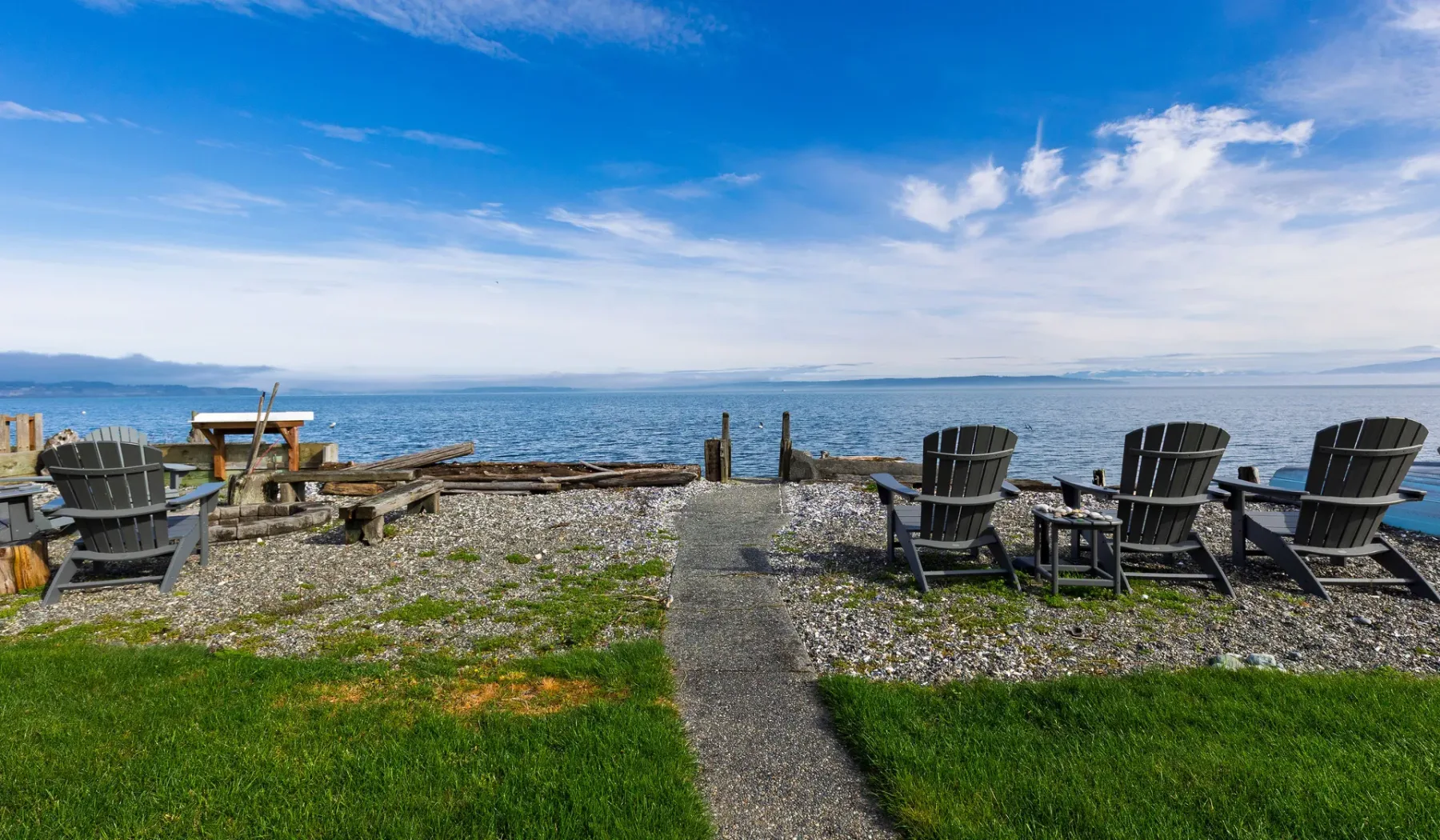 A gravel waterfront patio with outdoor seating overlooks the water.