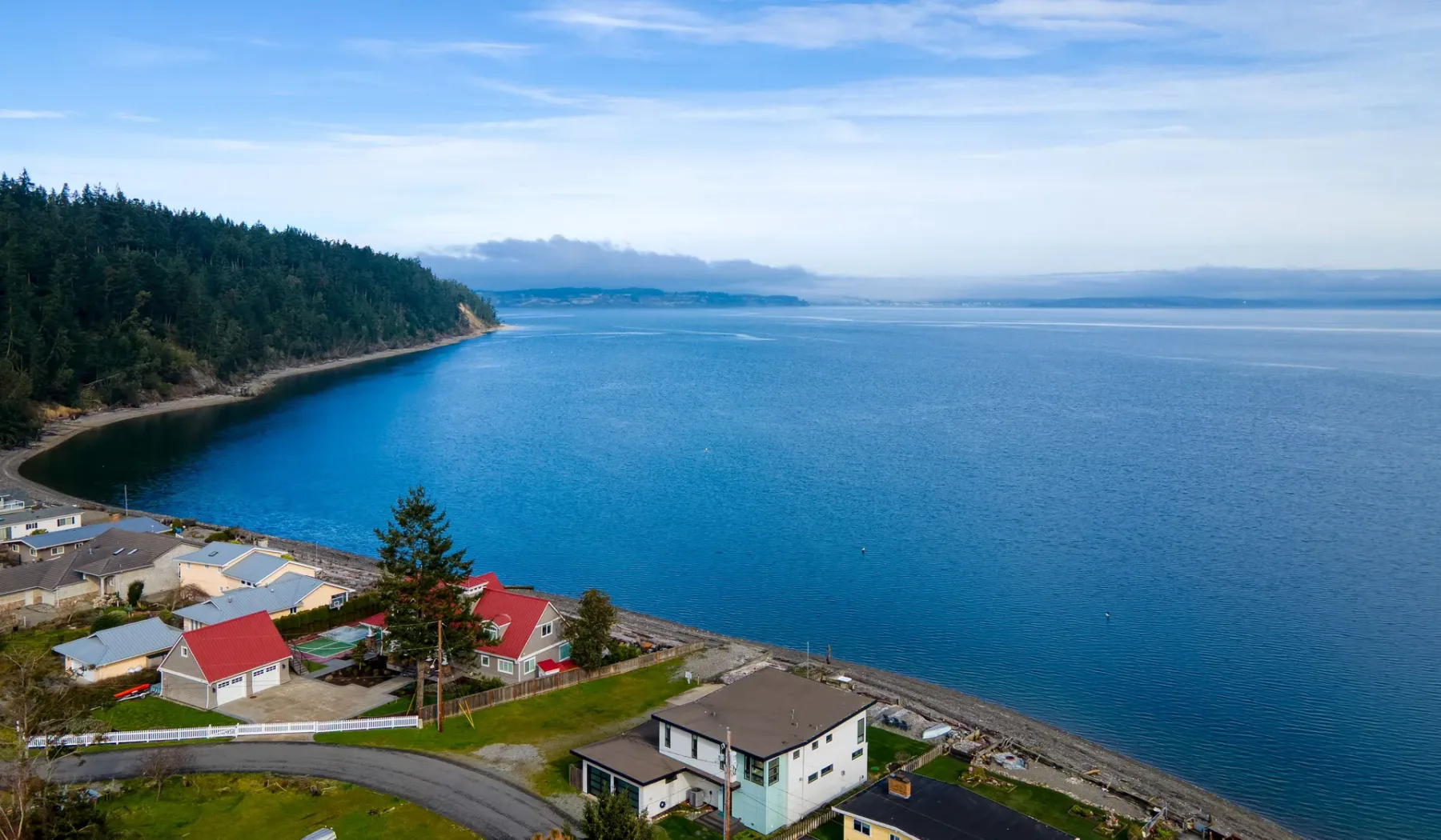 A coastal scene with a tree-covered shoreline beside calm blue water.