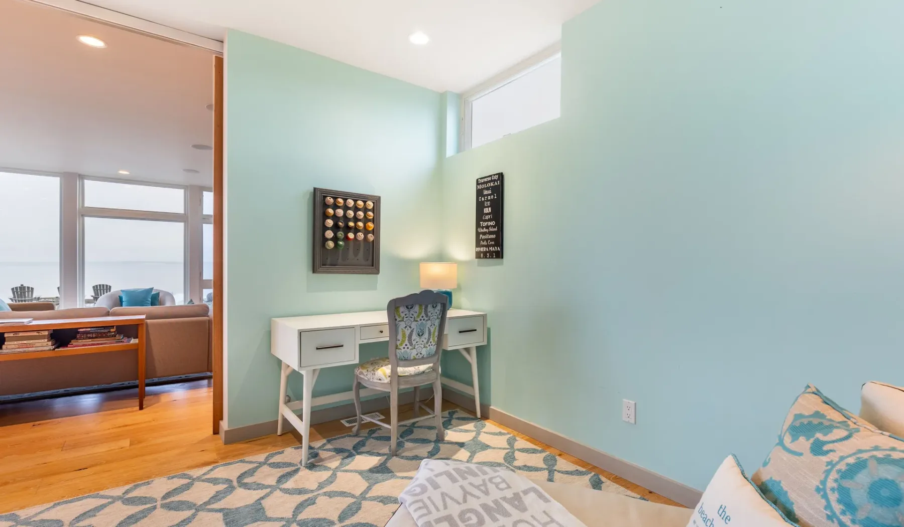 A mint-green study nook with a desk, chair, and wall art.