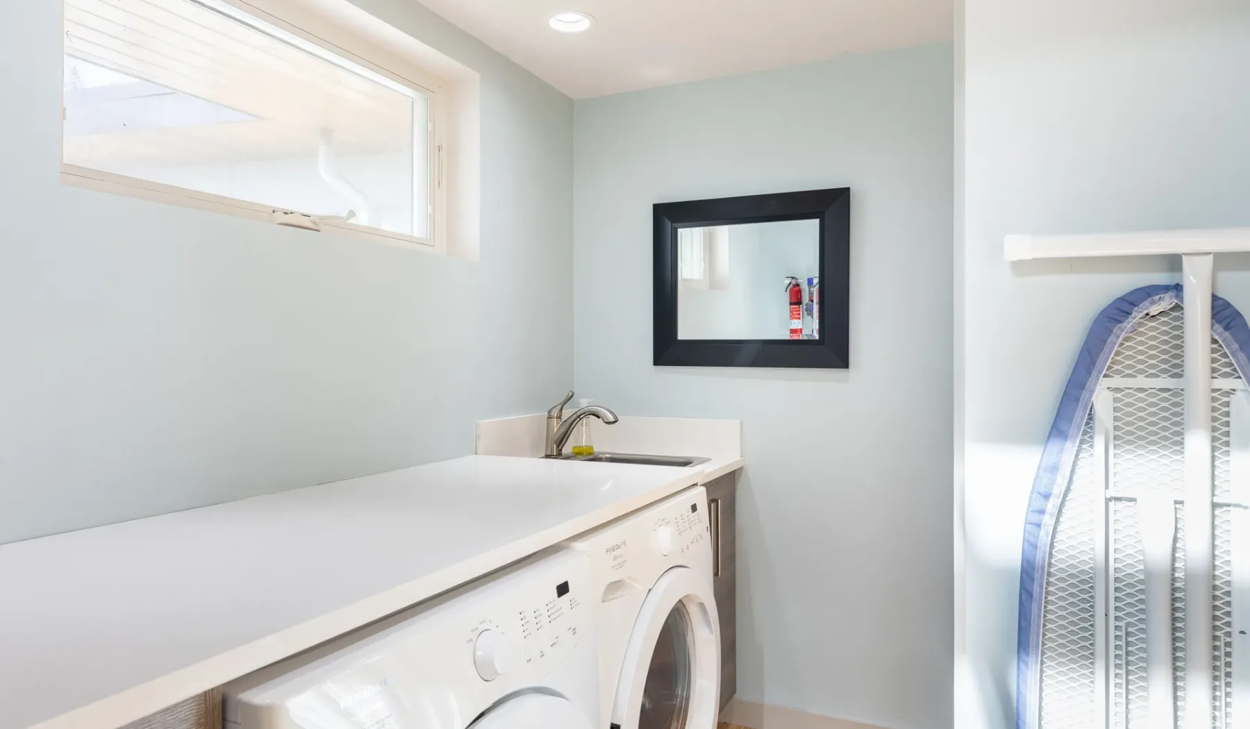 A laundry room with a washer and dryer beneath a countertop.