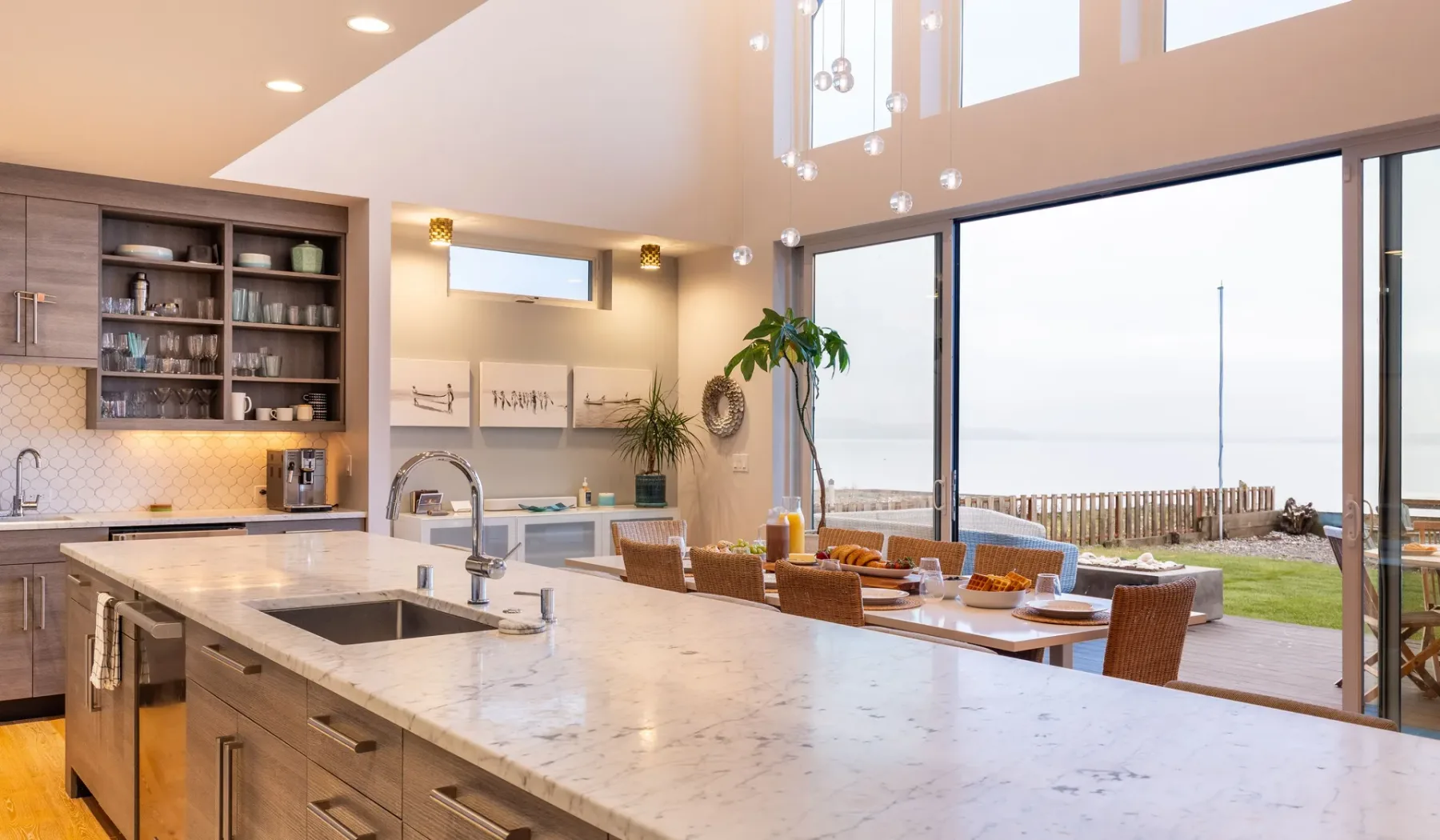 An open-plan kitchen and dining area overlooks the ocean through large windows.